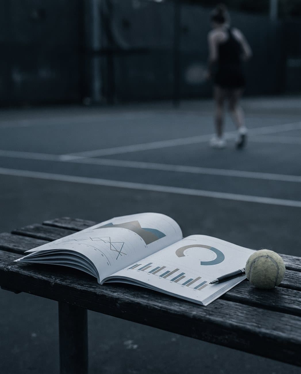 A printed match report open on a courtside bench next to a tennis ball